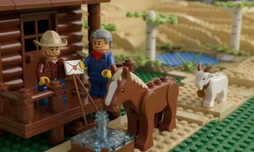 Tom, about 35, round-faced with stubble, wearing a worn beige hat, red-and-blue plaid shirt and brown leather vest, smiling but focused, holds a sealed letter in one hand and his horse's reins in the other; Maple, a broad-chested chestnut with a pale blaze, drinks from a wooden trough in the foreground; an older relay master of about 50 with graying hair, overalls and a scarf stands on the small wooden porch reaching for the letter; a small white kid with a wooden tag on its neck heads down the dusty path toward the farm; the setting is a rustic wooden relay station with a wide porch, barrels, a trough, a dusty trail across golden plains, cotton birches by a pond and a low rocky hill; Tom has arrived at dusk, dusty from a sandstorm, handing the sealed letter to the relay master as warm sunset light casts long shadows and calm returns.